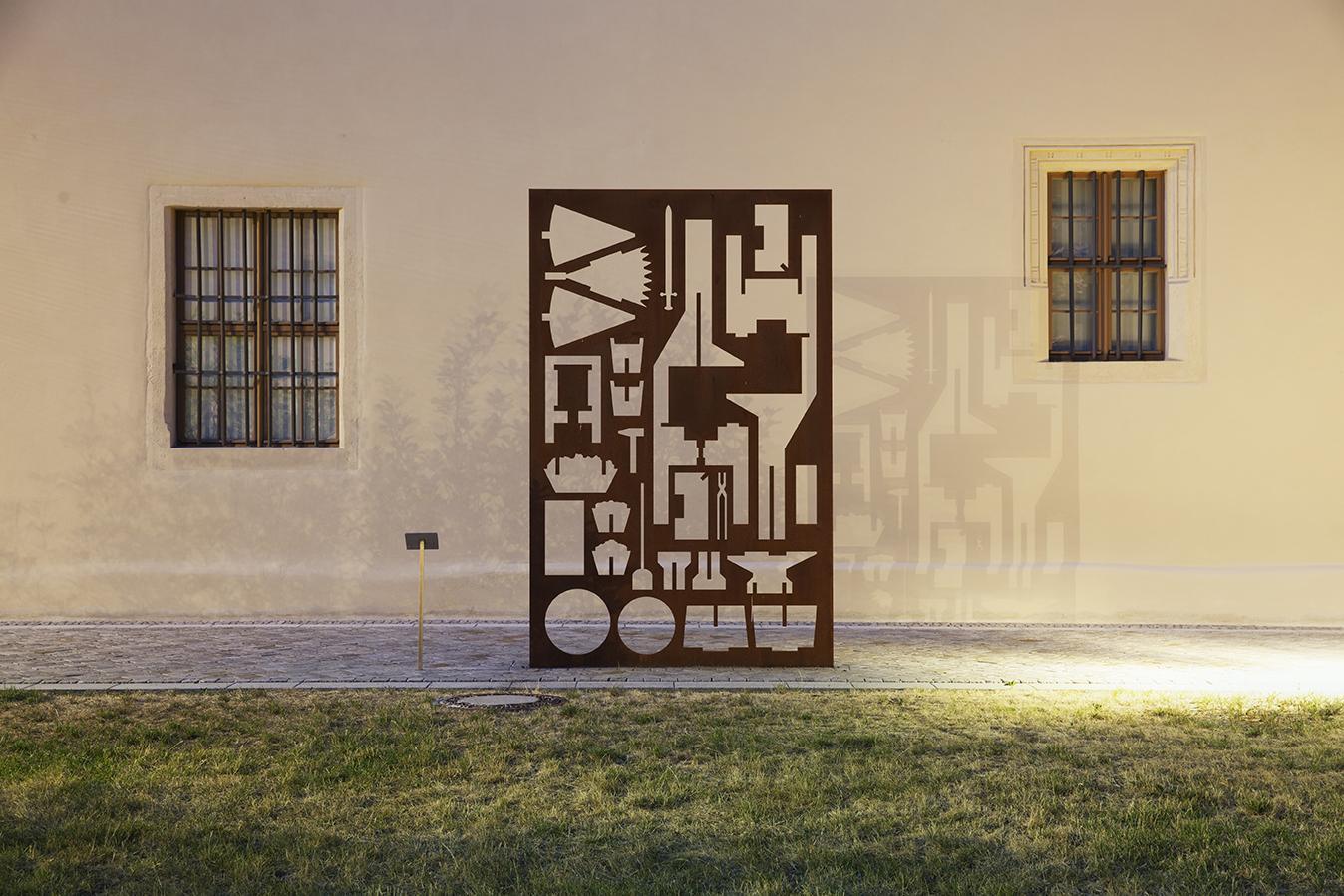 Denkmal "Schwester zu Pflugscharen", im Vordergrund Rasen, im Hintergrund Hauswand