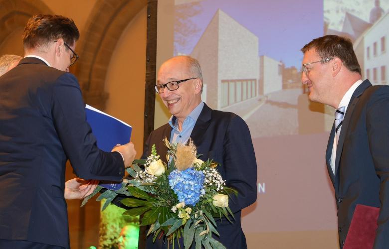 3 Menschen, Mensch in der Mitte (Dr. Rhein) bekommt Preis überreicht