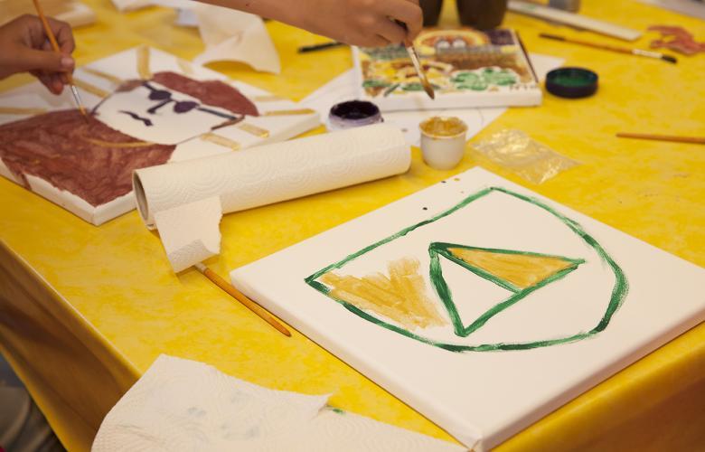gelber Tisch mit angefangenem selbst gemalten Wappen auf Leinwand