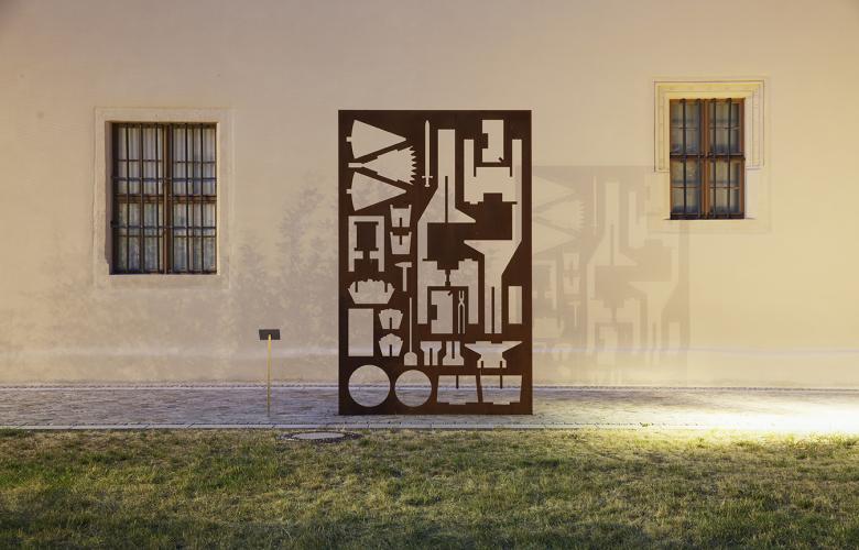 Denkmal "Schwester zu Pflugscharen", im Vordergrund Rasen, im Hintergrund Hauswand
