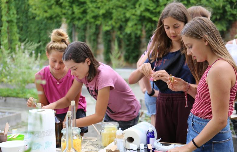 vier junge Mädchen experimentierend mit Ölen, Düften und Kräutern