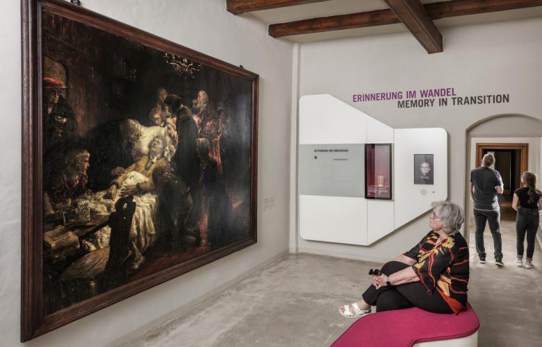 links großes Gemälde von Luthers letzter Stunde, rechts sitzt eine Person davor, weiße Wände