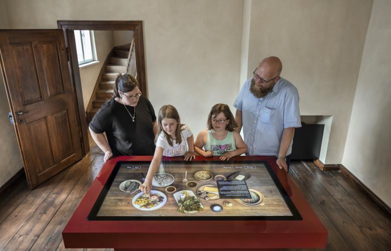 zwei Erwachsene und zwei Kinder erkunden den digitalen Esstisch
