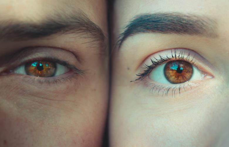 zwei Gesichter aneinander geschmiegt, ganz nah, nur jeweils ein Auge + Brauen