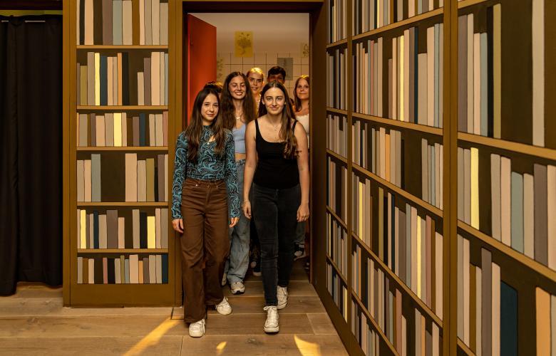 Gruppe Jugendlicher mittig, links und rechts hohe Bücherwände