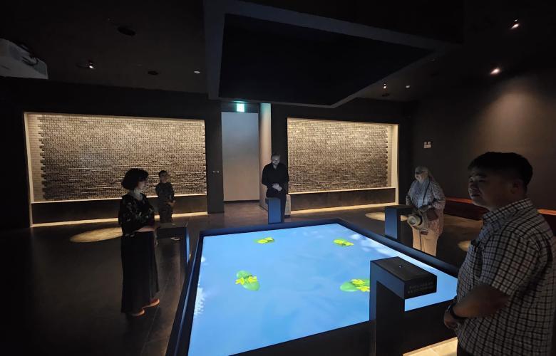 dunkler Ausstellungsraum, großer digitaler Tisch mittig