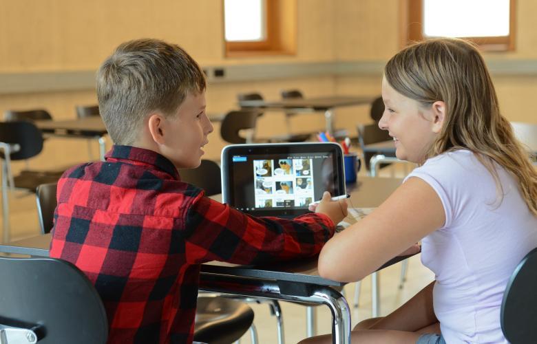 zwei Kinder sitzen an einem Laptop und gestalten einen Comic