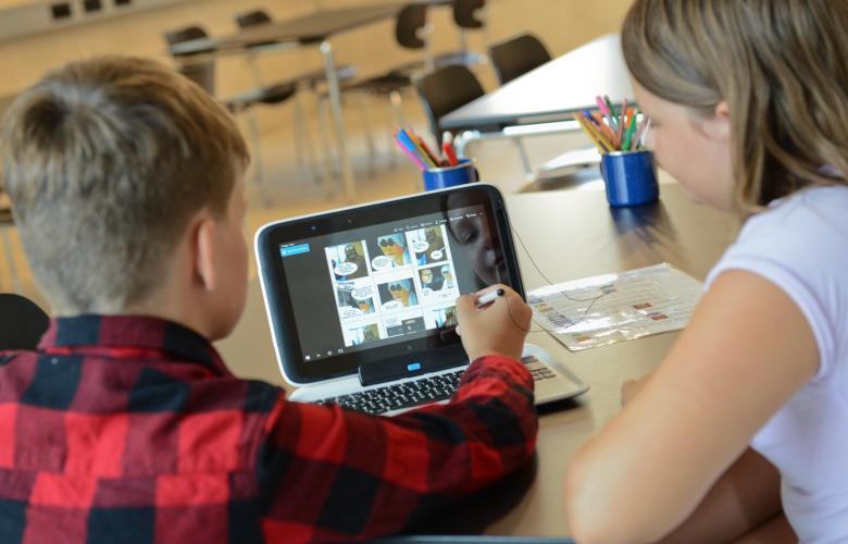 Junge und Mädchen sitzen vor einem Laptop und gestalten einen Comic