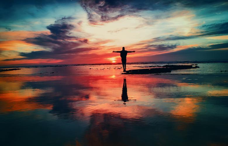 Silhouette eines Menschen vor einem Sonnenuntergang, am Meer