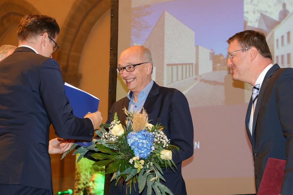 3 Menschen, Mensch in der Mitte (Dr. Rhein) bekommt Preis überreicht