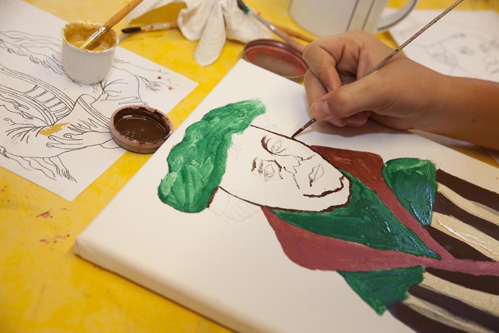 auf Leinwand mit Wasserfarben gemalter Luther, gelbe Tischdecke, viele Materialien drumerhum