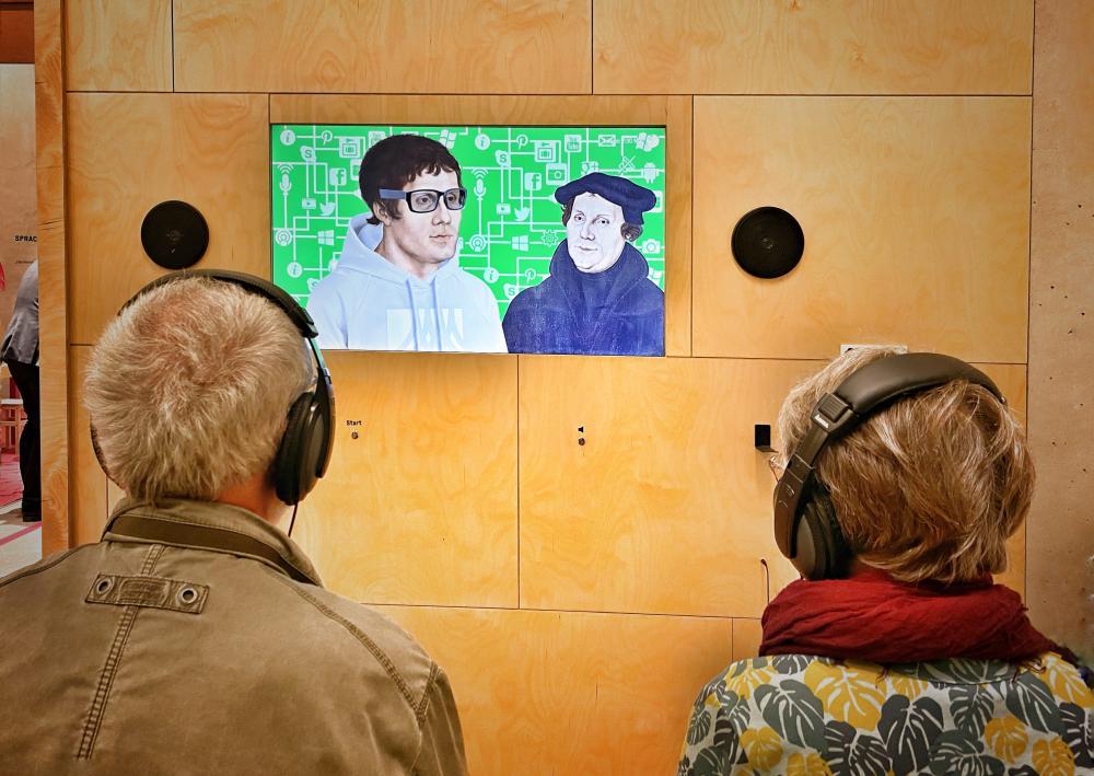 Zwei Besucher schauen den Introfilm zur Ausstellung.