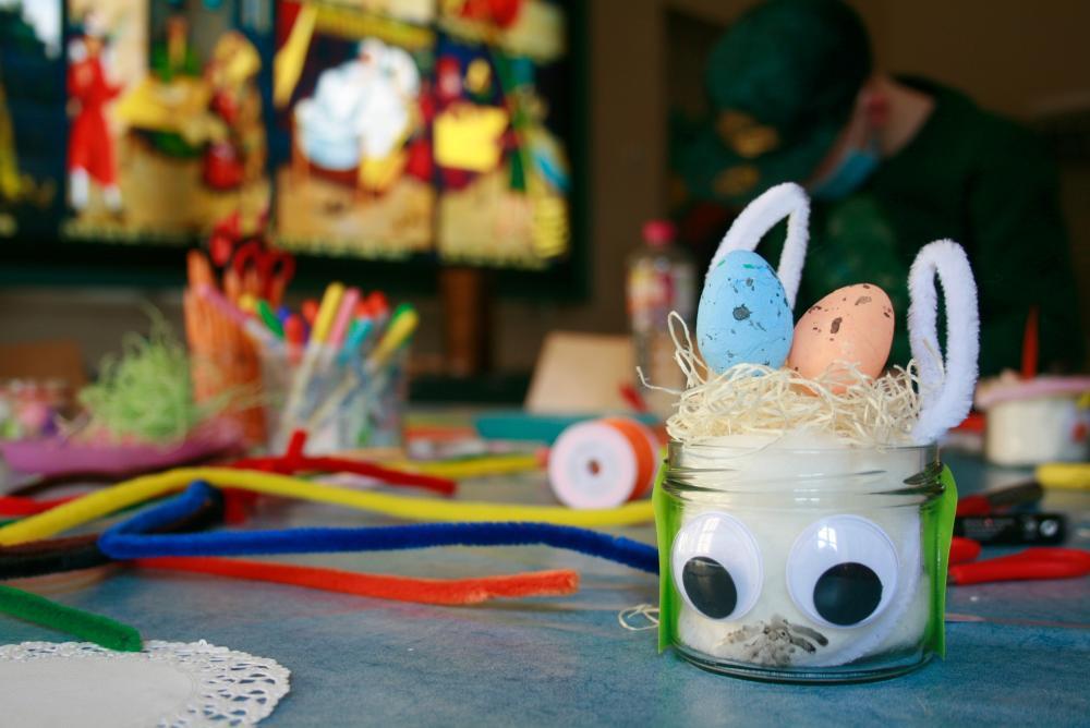 gebastelter Osterhase aus Glas rechts, links Bastelmaterialien auf dem Tisch