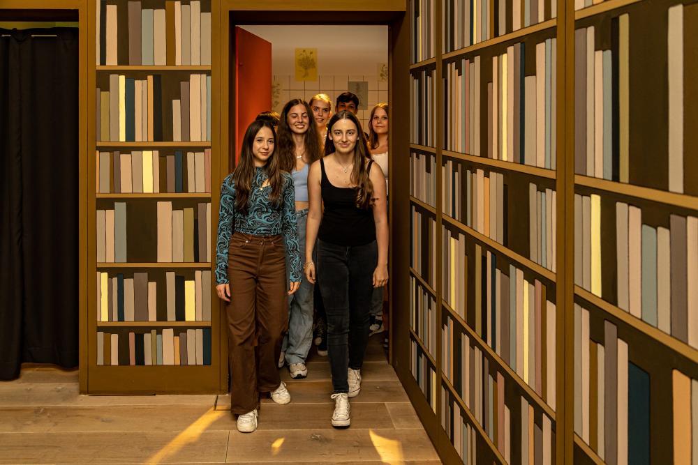 Gruppe Jugendlicher mittig, links und rechts hohe Bücherwände
