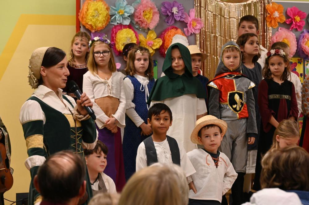 eine Frau in Tracht spricht in Mikro, im Hintergrund große Kindergruppe
