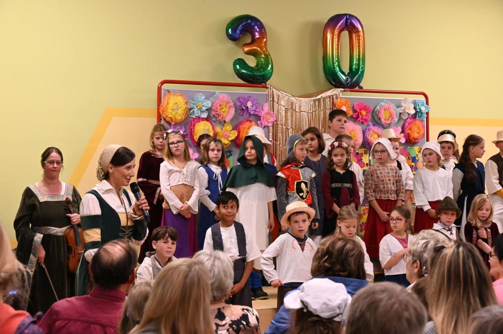 große Kindergruppe steht vor einer großen 30 aus Luftballons