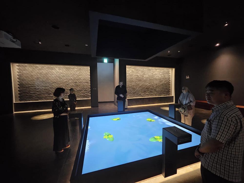 dunkler Ausstellungsraum, großer digitaler Tisch mittig