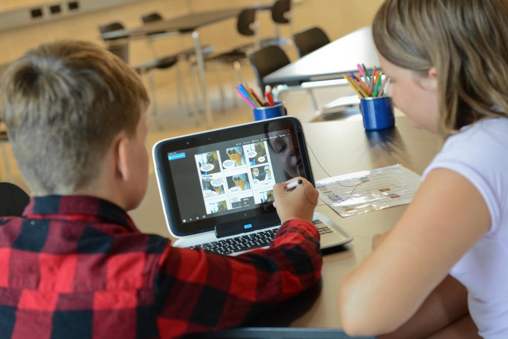 Junge und Mädchen sitzen vor einem Laptop und gestalten einen Comic