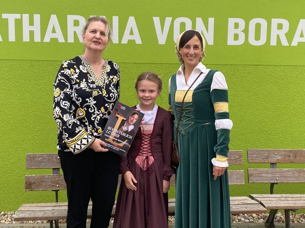 grüner Hintergrund, 2 Frauen stehen neben einem Mädchen