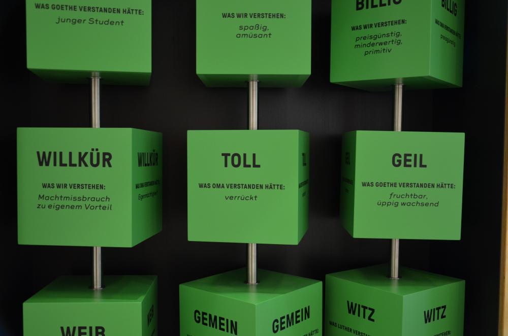 grüne große Würfel an Stangen, zum Drehen. auf allen Seiten stehen Worte mit Erklärungen