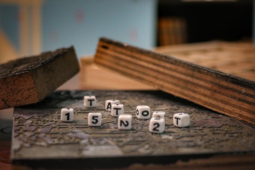 kleine Buchstabenürfel liegen auf einer Platte und ergeben "Tatort 1522"