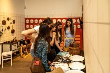 Gruppe Jugendlicher stehen in einer nachgebauten Küche um einen Tisch