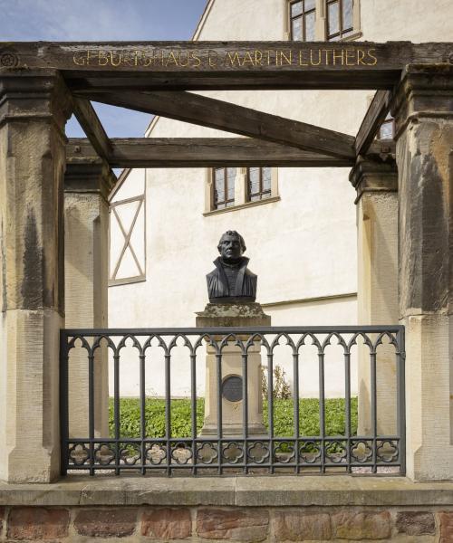 Büste Luthers im Fokus, Zaun davor, im Hintergrund Hauswand